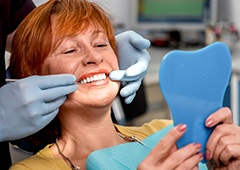 Senior woman in dental chair looking at her smile